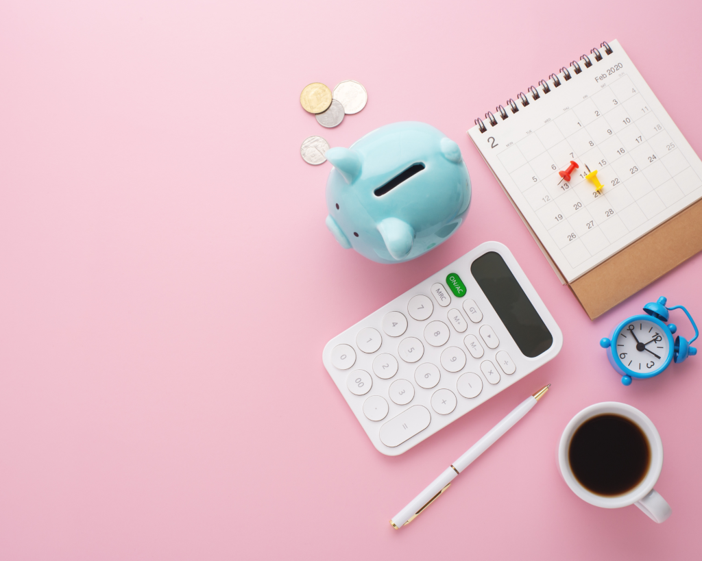 calculator, calendar, penny pig and other objects on a pink background