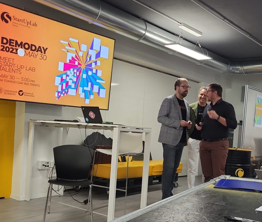 3 men speaking in a classroom with a screen next to them describing the event